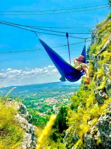 Pensiunea Valea Șușiței, Ciubar, Sauna, ATV, Safarii Jepp Offroad Ghid Turistic, Climbing, Rafting, Paragliding في تارغو جيو: شخص في أرجوحة على جبل