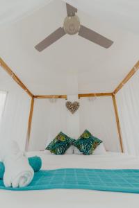 1 dormitorio con ventilador de techo y 1 cama con almohadas en UUTTAAKA Eco-Hotel, en Palomino