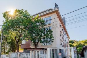 a building with a white fence next to a tree at Bem localizado - @stayhousetemporada in Canela