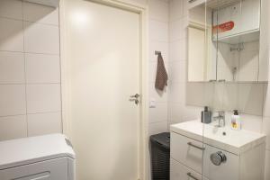 een witte badkamer met een wastafel en een spiegel bij Tampere Kannen Topaasi - Apartment by the Nokia Arena in Tampere