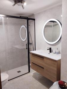 uma casa de banho com um chuveiro, um lavatório e um espelho. em Apartamento en San Sebastián con parking em Loyola