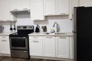 eine Küche mit weißen Schränken und einem schwarzen Kühlschrank in der Unterkunft Basement Suite 1 queen bedroom(Brand New House) in Coquitlam
