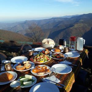 une table avec des assiettes de nourriture au sommet d'une montagne dans l'établissement SIRT BUTİK HOTEL, à Akcaabat