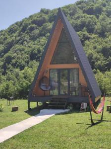 una pequeña casa con un techo triangular en la hierba en Canyon garden en Martvili
