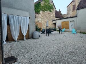a patio with white curtains and a table and chairs at La Feuillette in Maligny