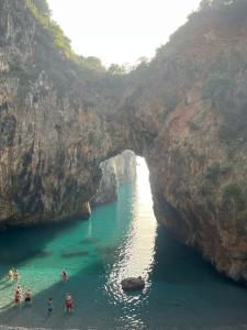 um grupo de pessoas em pé na água em uma caverna em La Conchiglia em San Nicola Arcella