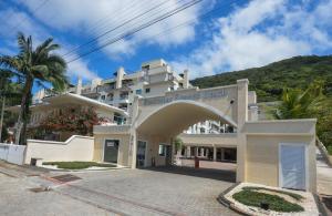 a large white building with a mountain in the background at 182G - Excelente cobertura em condomínio completo in Bombinhas