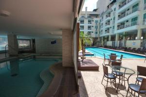 a swimming pool with chairs and a table next to a building at 182G - Excelente cobertura em condomínio completo in Bombinhas