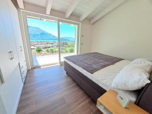 a bedroom with a bed and a large window at Immobillario - Lakes Dream in Domaso