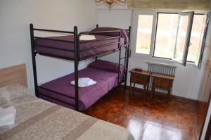 een slaapkamer met 2 stapelbedden met paarse lakens bij Casa completa e independiente en centro de Melide in Melide