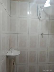 een wit betegelde badkamer met een wastafel en een douche bij Casa em Diamantina in Diamantina