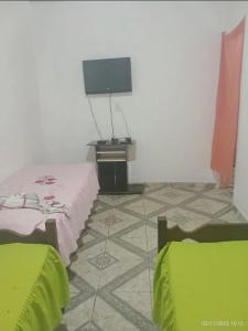 een kamer met 2 bedden, een tv en een tegelvloer bij Casa em Diamantina in Diamantina