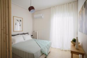 ein weißes Schlafzimmer mit einem Bett und einem Fenster in der Unterkunft H Experience - Funky 1BD apartment in vibrant Nea Smirni in Athen