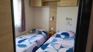 two beds sitting next to each other in a room at Mobil home 3 ch domaine de kerlann pont aven wifi inclu in Pont-Aven