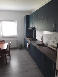 - une cuisine avec des placards bleus, une table et un évier dans l'établissement Apartament b&b Rădăuți, à Rădăuţi