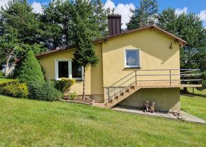 a small yellow house with two figurines in front of it at Domek Karłowo u Eli in Sierakowice