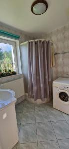 a bathroom with a shower curtain and a washing machine at Domek Karłowo u Eli in Sierakowice +10 photos
