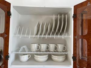 un armario con un montón de tazas y utensilios en Casa Blanca Hostal, en Rionegro