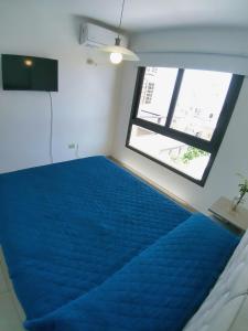 Un dormitorio con una cama azul y una ventana en Departamento Entero con Pileta Calasanzs en Córdoba