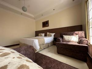 a bedroom with a bed and a couch and a chair at mnarat al madina in Al Madinah