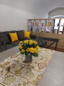 un soggiorno con un vaso di fiori gialli su un tavolo di La casina in città - The little flat in town ad Alessandria