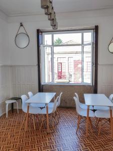 a room with tables and chairs and a window at OLOPO Hostel in Porto
