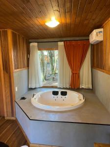 uma grande banheira num quarto com uma janela em Hotel Cabanas Glamour em Gramado
