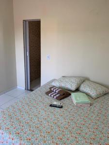 a bed with a remote control and books on it at Pousada Jesus Me Deu in Iguatu