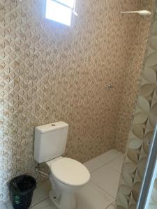 a bathroom with a white toilet and a window at Pousada Jesus Me Deu in Iguatu