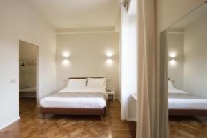 1 dormitorio con 2 camas, sábanas blancas y suelo de madera. en Le Due Piazze, en Génova