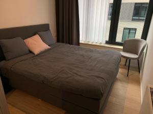 een bed in een slaapkamer met een stoel en een raam bij Stijlvol appartement in trendy wijk Oostende in Oostende