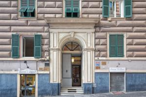 un ingresso a un edificio con finestre con persiane verdi di Le Due Piazze a Genova