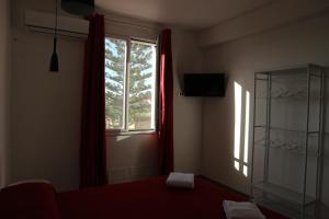 a bedroom with a window and a red curtain at L'Atelier di Vittoria in Carini