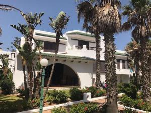 un edificio blanco con palmeras delante en Villa haut standing Mdiq Fnideq Bahia Smir, en Dar Merah Deriba