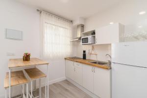 una cocina blanca con armarios blancos y fregadero en Precioso apartamento con espectaculares vistas, en Santander