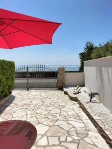 - un parasol rouge sur une terrasse avec l'océan en arrière-plan dans l'établissement Venez vous ressourcer sur les falaises de Meschers, à Meschers-sur-Gironde