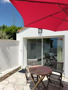 - un parasol rouge sur une terrasse avec des chaises et une table dans l'établissement Venez vous ressourcer sur les falaises de Meschers, à Meschers-sur-Gironde