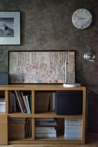 une télévision sur une étagère en bois avec une horloge sur le mur dans l'établissement Olga apartment, à Riga