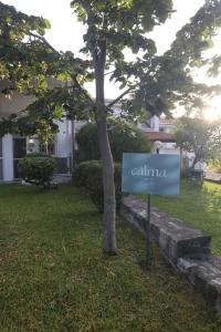 a sign in the grass next to a tree at Calma Resort in Skála Foúrkas
