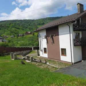 una casa blanca y marrón con una colina al fondo en Guest House Stari Druzy en Slavske