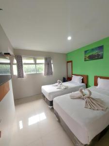 two beds in a room with green walls at The Aurora by Makati in Lembang