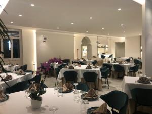 ein Restaurant mit weißen Tischen, Stühlen und Blumen darauf in der Unterkunft Hotel La Silvana in Selva di Fasano