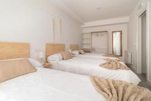 Habitación blanca con 2 camas con mantas. en Amplio y bonito apartamento en La Maruca, en Santander