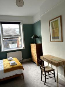 a bedroom with a bed and a desk and a window at Suze's Stays in Harrogate