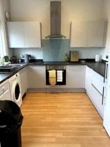 cocina con armarios blancos y suelo de madera en Suze's Stays en Harrogate
