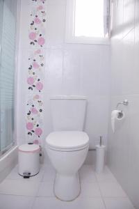 La salle de bains blanche est pourvue de toilettes et d'une fenêtre. dans l'établissement Sea Front Retreat, à Kavala