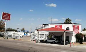 a white building with a car parked in front of it at Hotel Express Inn in Sabinas