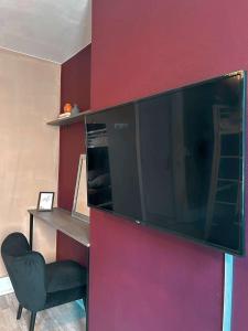 a large flat screen tv hanging on a red wall at Bel appartement sur Dunkerque in Dunkerque +1 photo