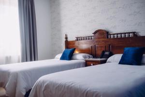 Hotel Cueli في Viveda: سريرين مع وسائد زرقاء في غرفة الفندق