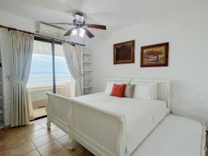 a white bedroom with a bed and a window at Live an adventure in Taboga 2 in Taboga